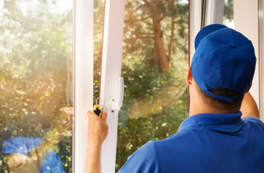 A man in blue shirt and cap looking out of window.
