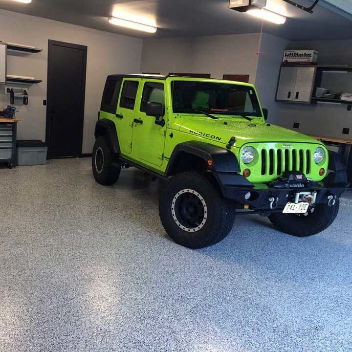 A jeep is parked in the garage with its door open.